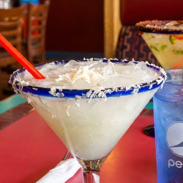 Two margaritas, one coconut and one spicy, with a Pepsi on a red table.
